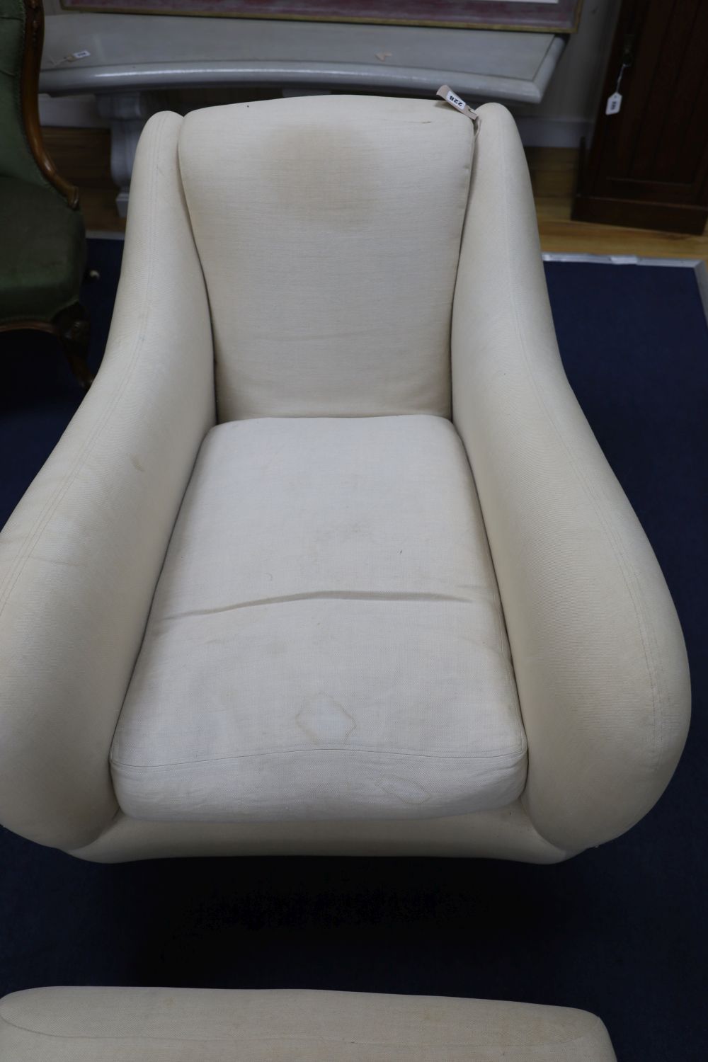 A contemporary upholstered club armchair and foot stool